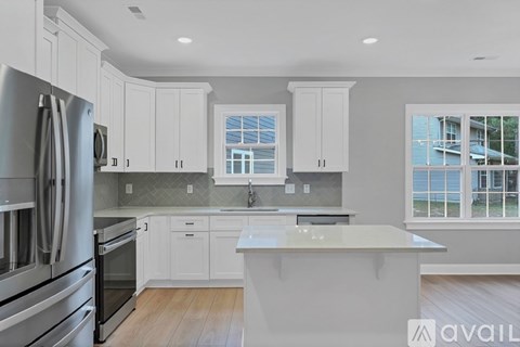 A modern kitchen with white cabinets and stainless steel appliances.
