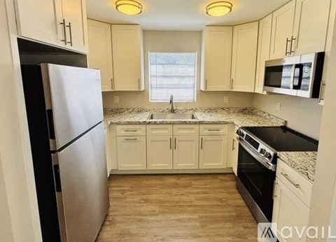 A kitchen with a black fridge, black stove, and white cabinets.