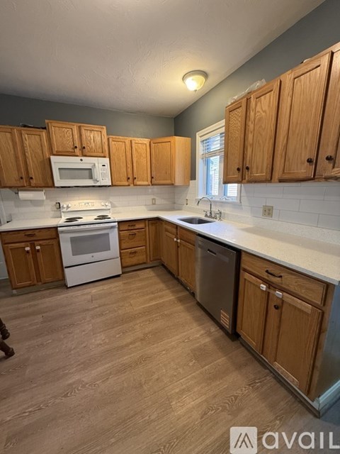 A kitchen with wooden cabinets and a white stove top oven.