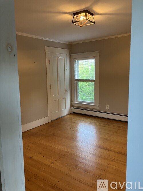 A room with wooden floors and a window with a view of greenery outside.