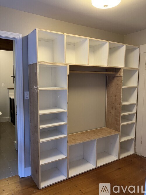 A room with a white shelving unit and a door open.