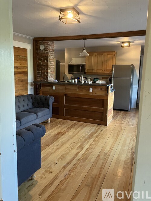 A kitchen with a blue couch and wooden floors.