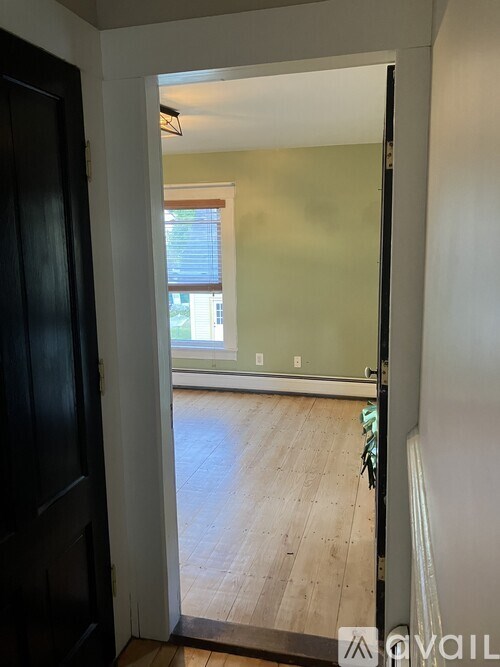A room with a wooden floor and a window with blinds.
