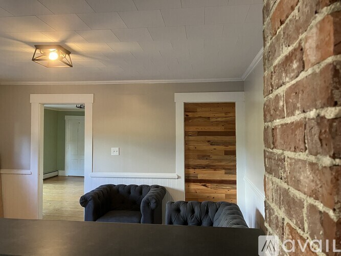 A black couch is in front of a wooden wall.