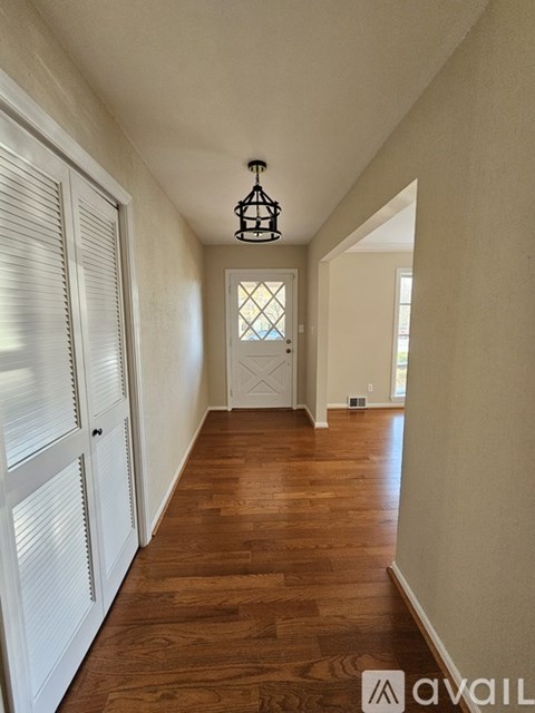 A hallway with a wooden floor and white walls.