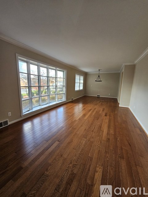 A room with wooden flooring and a large window.