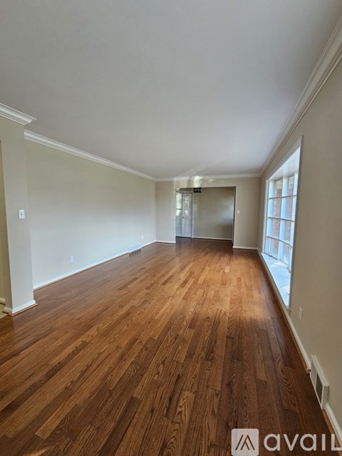 A room with wooden flooring and a door leading to another room.