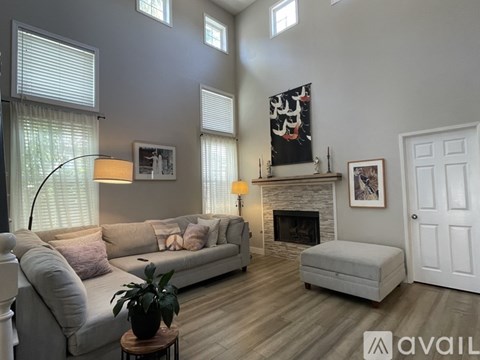A living room with a grey couch, a fireplace, and a painting on the wall.