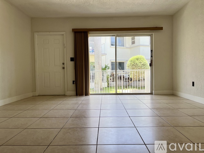 A room with a tiled floor and a sliding glass door leading to a balcony.