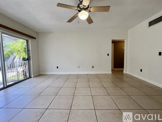 A spacious room with a ceiling fan and sliding glass doors leading to a patio.