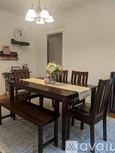 A wooden dining table with chairs and a vase of flowers on top.