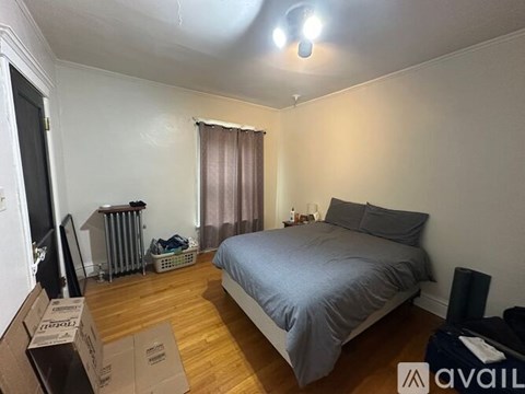 A room with a bed, a window with curtains, and a radiator.