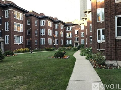 A brick apartment building with a well kept lawn in front.