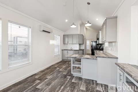 A kitchen with white cabinets and a wooden floor.