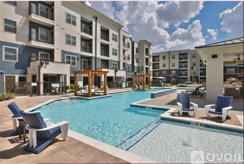 A large swimming pool surrounded by blue lounge chairs and wooden structures.
