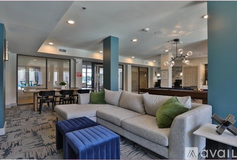 A living room with a grey couch and a blue ottoman.