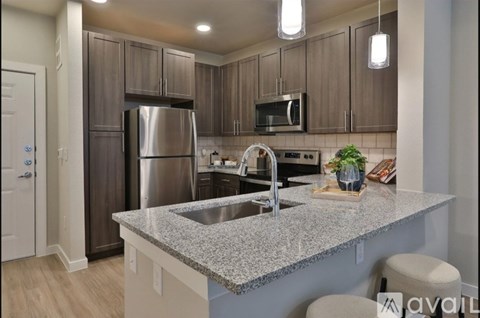 A kitchen with a granite countertop and stainless steel appliances.