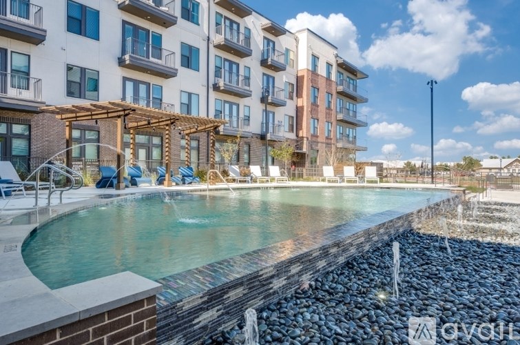 A pool area with a waterfall and a building in the background.