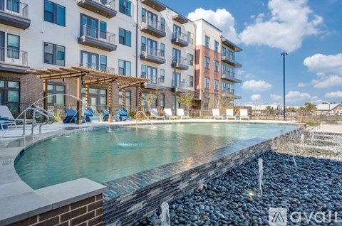 A pool area with a waterfall and a building in the background.