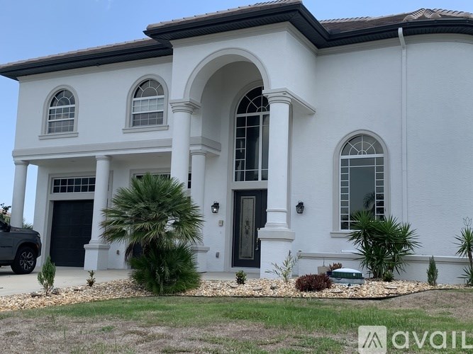 A white house with a black garage door and a black car parked in front.