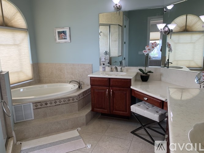 A bathroom with a tub, sink, and mirror.