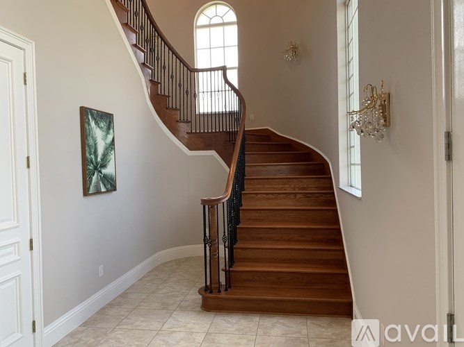 A staircase with a wooden handrail and a chandelier in the background.