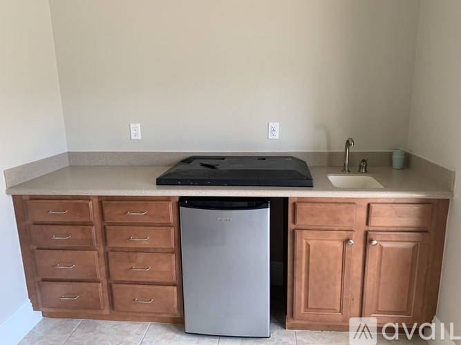 A kitchen with a black dishwasher and wooden cabinets.