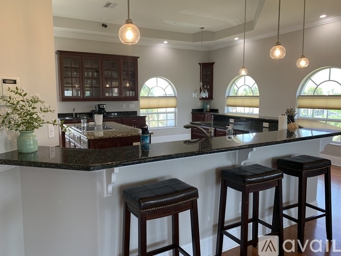 A kitchen with a bar area and three stools.