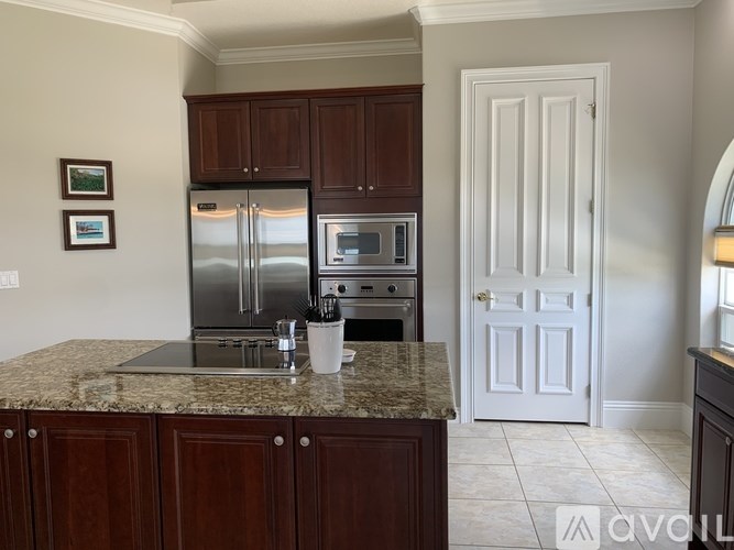 A kitchen with a granite countertop and dark brown cabinets.