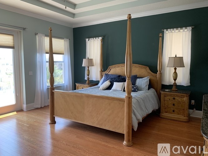 A bedroom with a large bed and two lamps.