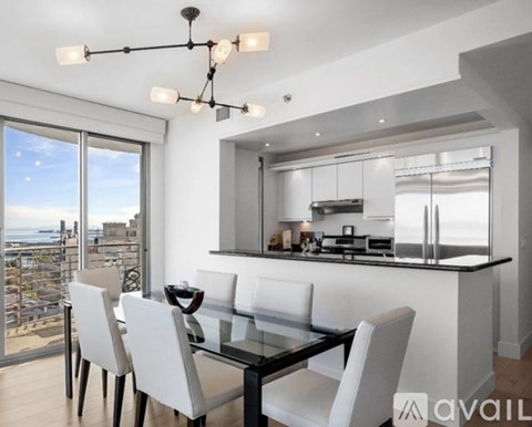 A modern kitchen with a glass table and chairs and a view of the city.