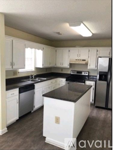 A kitchen with white cabinets and a black countertop.