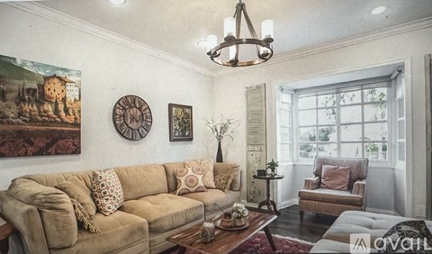 A living room with a beige couch, a chandelier, and a painting on the wall.