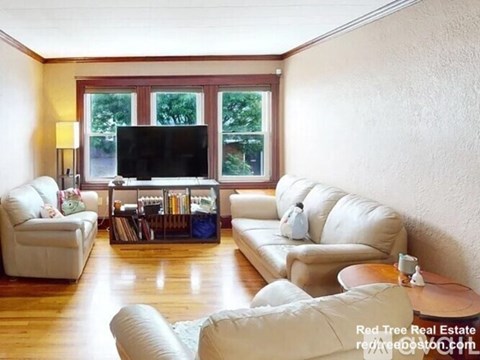 A living room with white furniture and a flat screen TV.