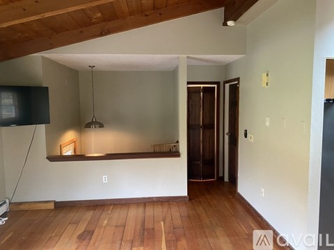 A living room with wood floors and a television.