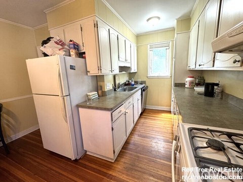 A kitchen with a white refrigerator and wooden floors.