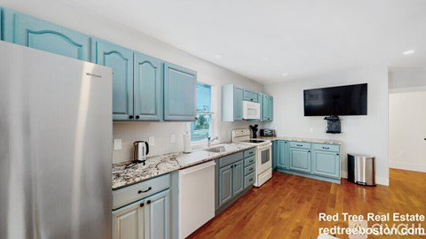 A kitchen with blue cabinets and a stainless steel refrigerator.