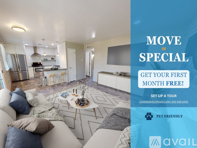 A living room with a couch, a coffee table, and a kitchen area in the background.