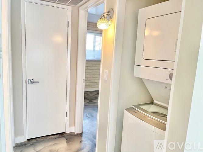 A white door is open to a hallway with a washer and dryer in the corner.