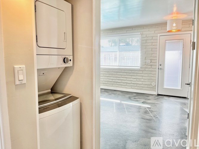 A white dishwasher is installed in a kitchen with a white door and a window with blinds.