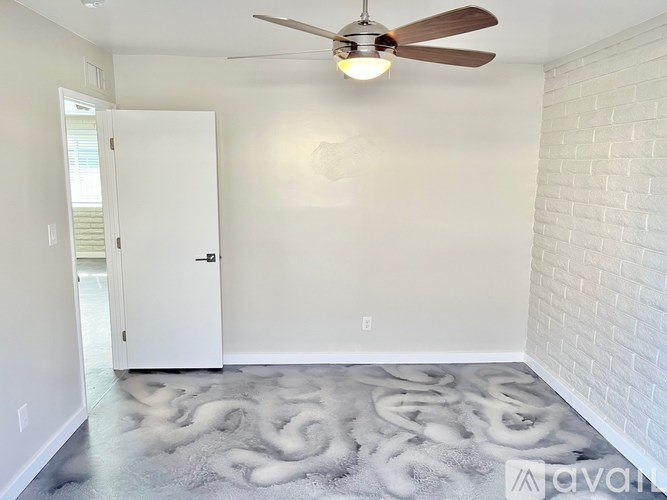 A room with a ceiling fan and a white rug on the floor.