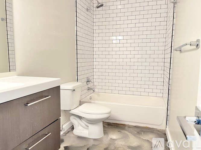 A white toilet sits in a bathroom with a white tiled shower.