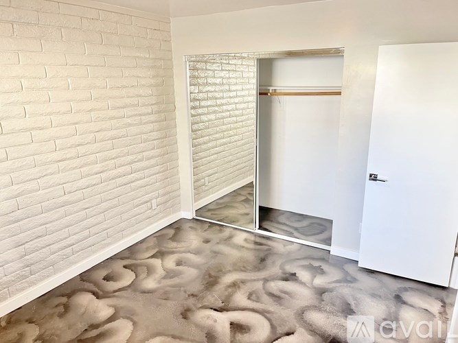 A room with a white brick wall and a grey carpet.