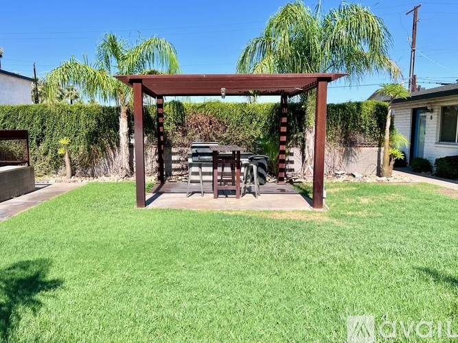 A backyard with a wooden pergola and a table under it.