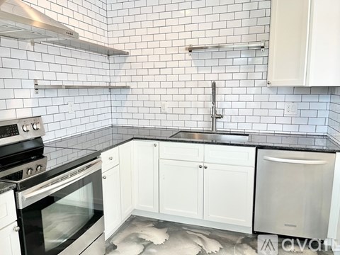 A kitchen with white cabinets and black appliances.