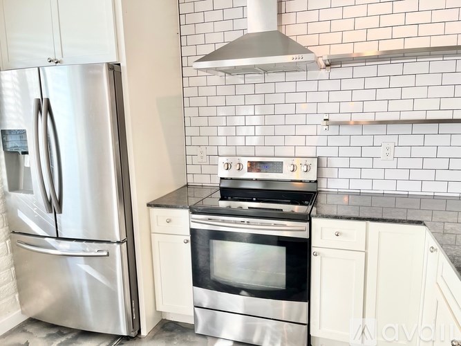 A kitchen with a stainless steel refrigerator and a stainless steel oven with a range hood above it.