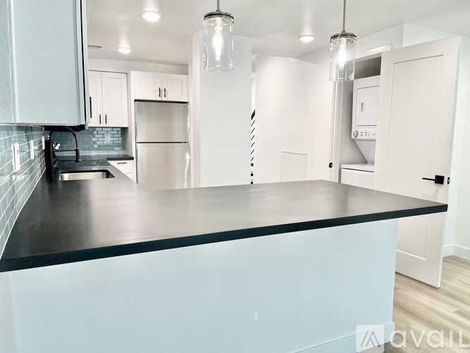A modern kitchen with a black countertop and white cabinets.