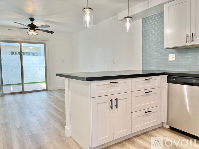 A kitchen with white cabinets and a black countertop.