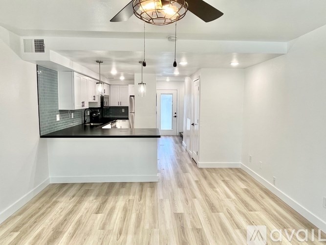 A spacious kitchen with a black countertop and wooden flooring.