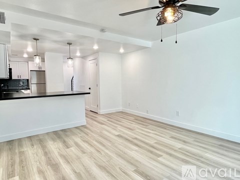 A spacious kitchen and living room with a ceiling fan and lighting fixtures.